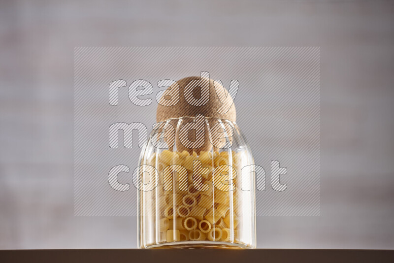 Raw pasta in glass jars on beige background