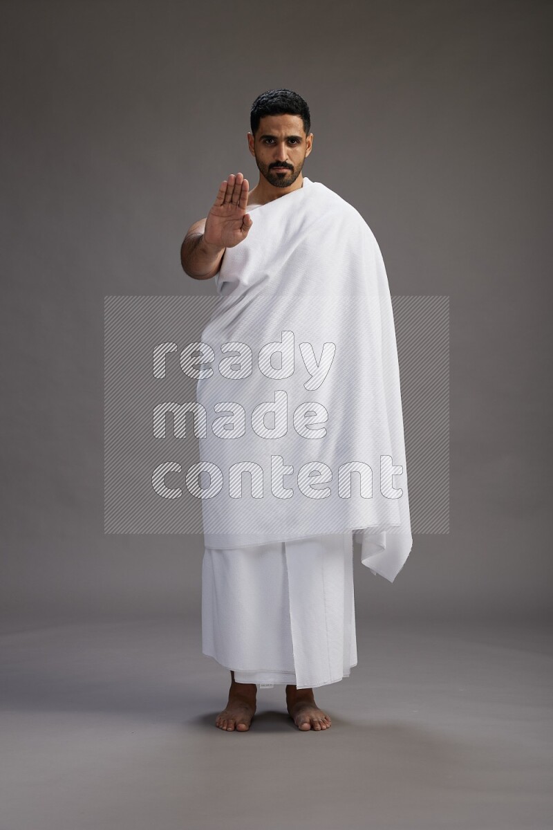 A man wearing Ehram Standing Interacting with the camera on gray background