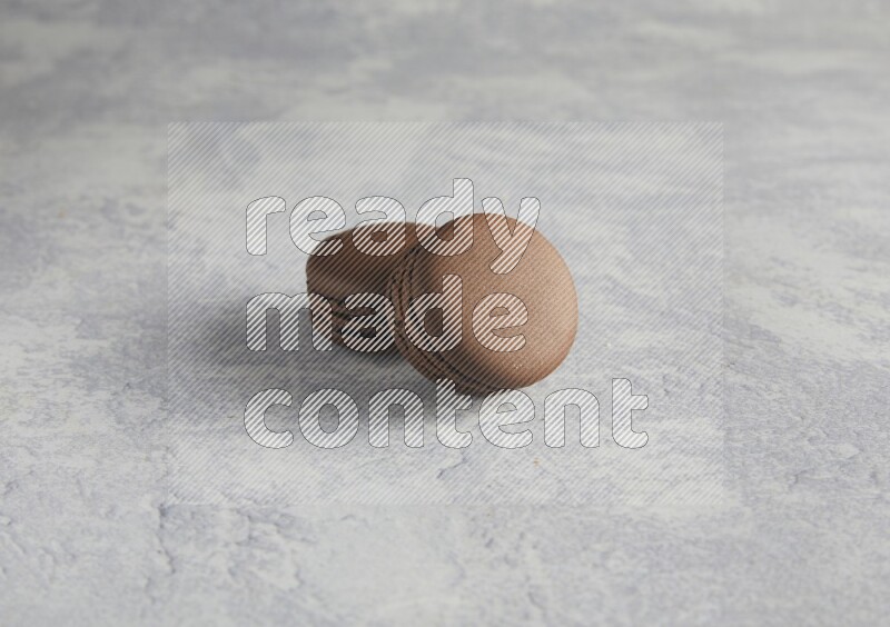 45º Shot of two Brown Dark Chocolate macarons  on white  marble background