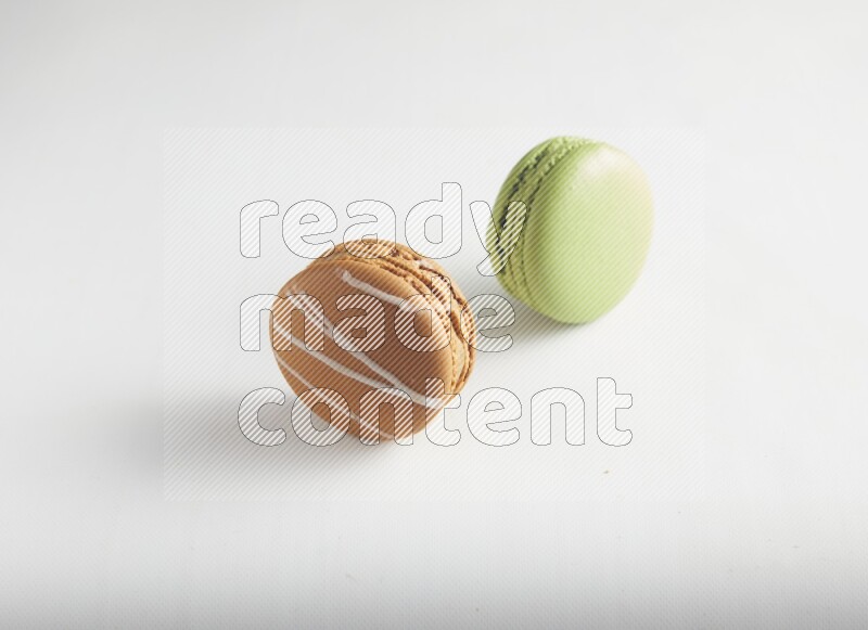 45º Shot of of two assorted Brown Irish Cream, and Green Pistachio macarons on white background