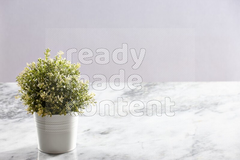 Artificial plant in white pot on grey marble background
