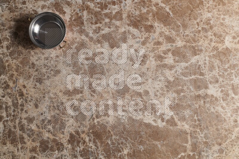 A small copper pot on beige marble background