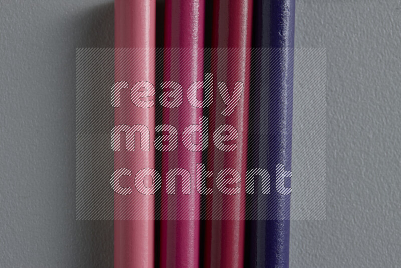 مجموعة من أقلام الرصاص الملونة مرتبة لتعرض تدرجا من اللون الوردي والأرجواني علي خلفية رمادية