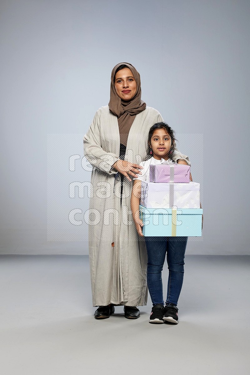 A girl giving a gift to her mother on gray background