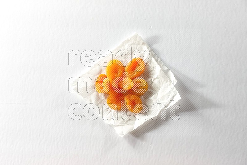 Dried apricots on a crumpled piece of paper on a white background in different angles