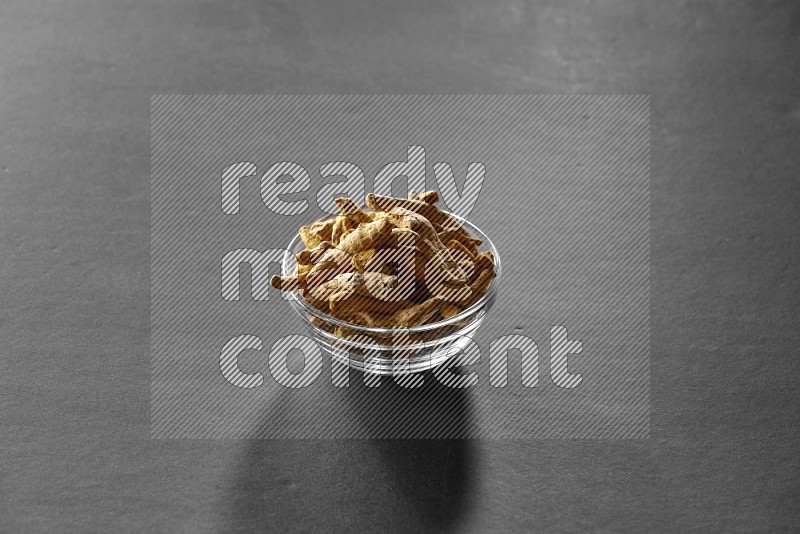 A glass bowl full of turmeric on black flooring