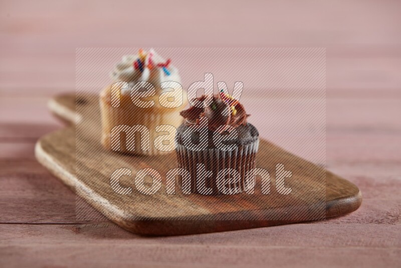 Chocolate mini cupcake topped with chocolate cream on a wooden board