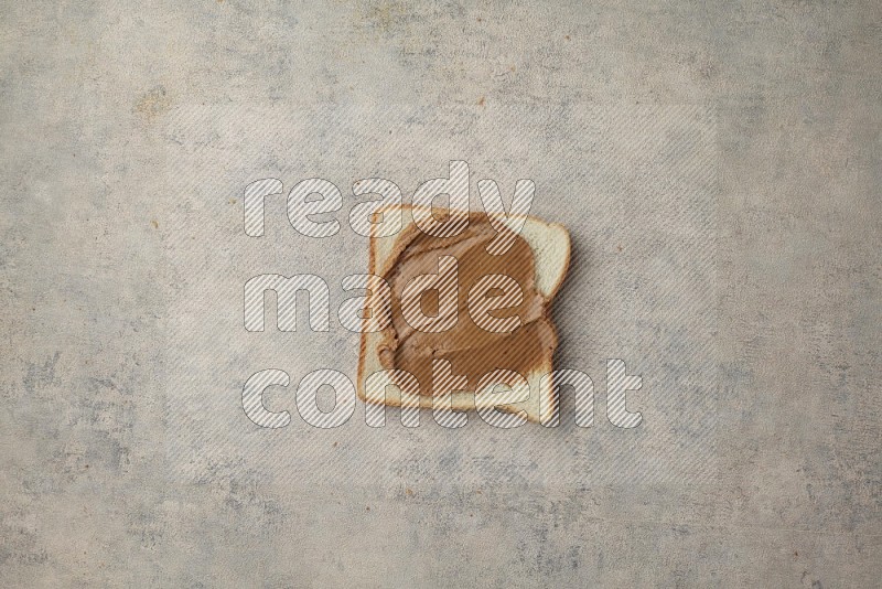 Creamy peanut butter on a white toast on a light blue textured background