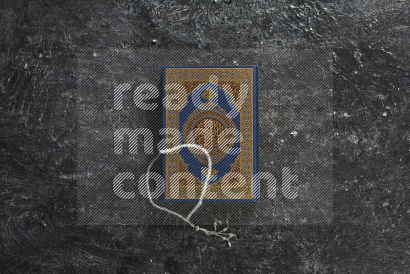 Quran with a prayer beads on textured black background