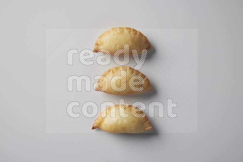 Three fried sambosa from a top angle on a white background