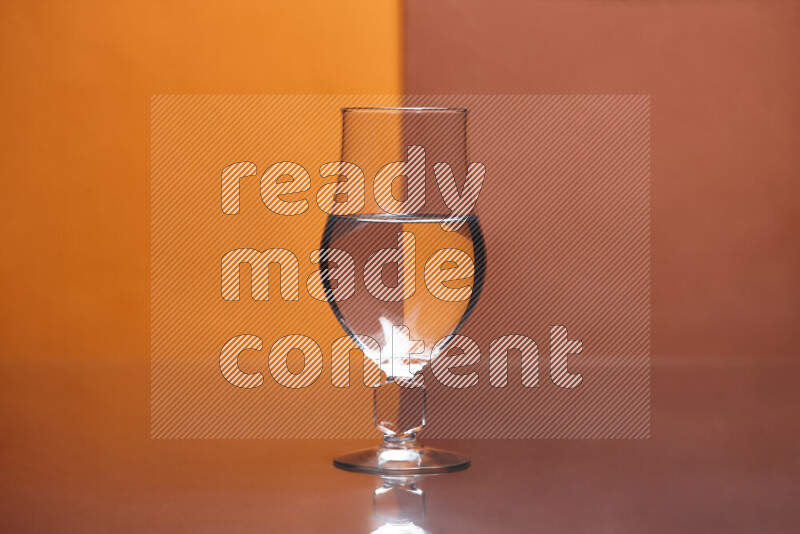 تظهر الصورة أواني زجاجية ممتلئة بالماء موضوعة على خلفية من اللونين البرتقالي والبرتقالي الغامق