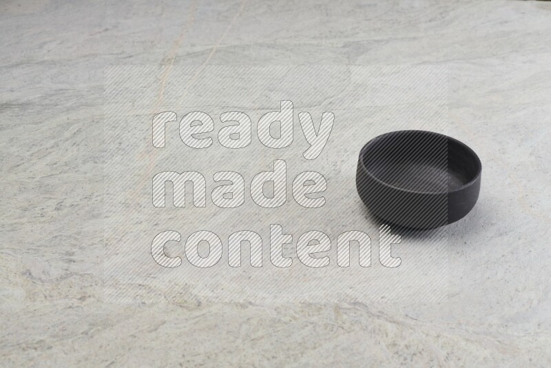 A black pottery bowl on grey marble background