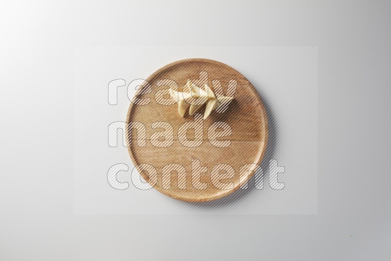 Three Sambosas on a wooden round plate on a white background