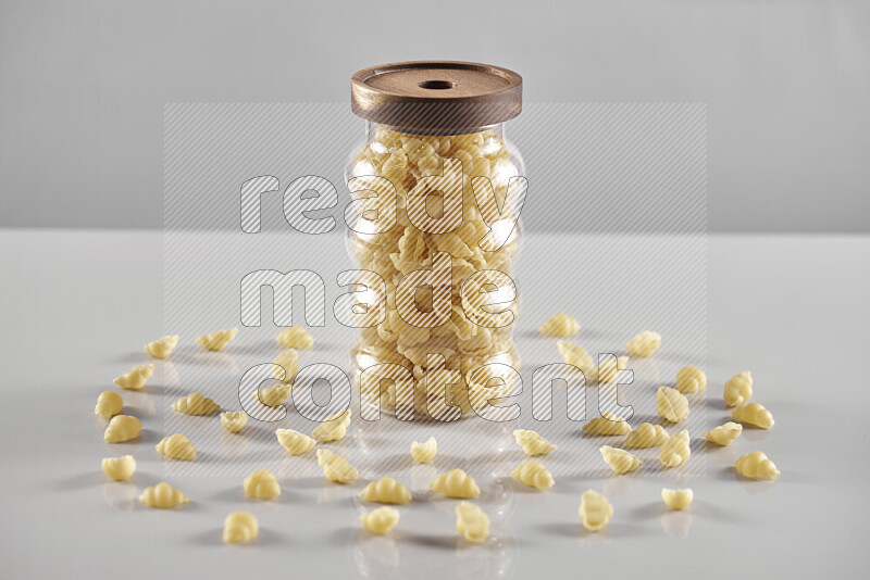 Raw pasta in a glass jar on light grey background