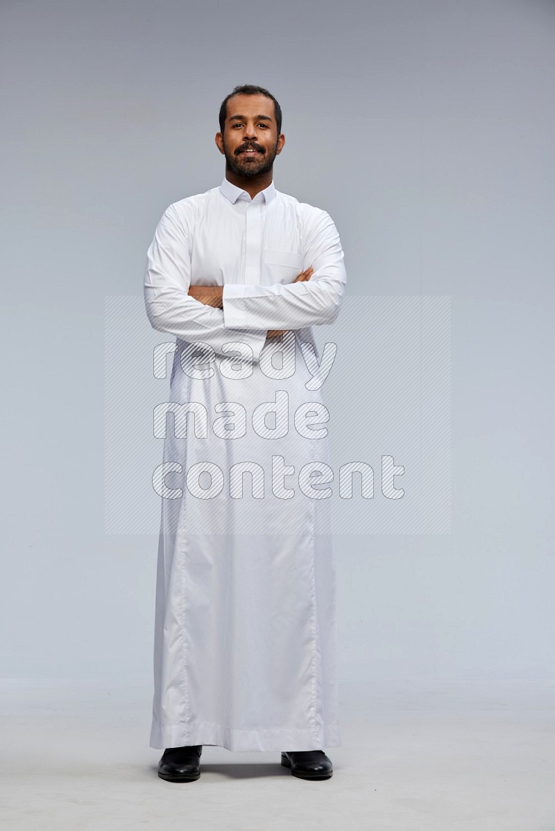 Saudi man wearing Thob standing with crossed arms on Gray background