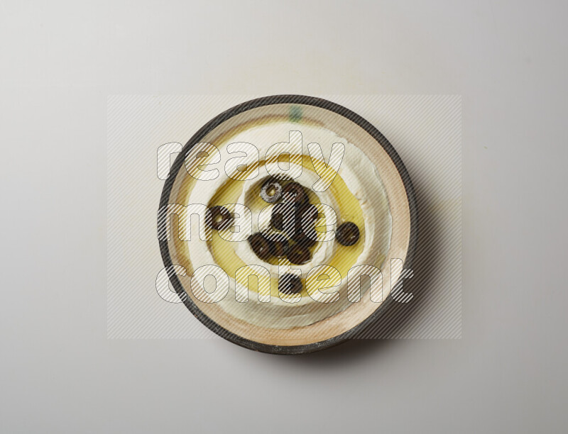 Lebnah garnished with sliced olives in a pottery plate on a white background