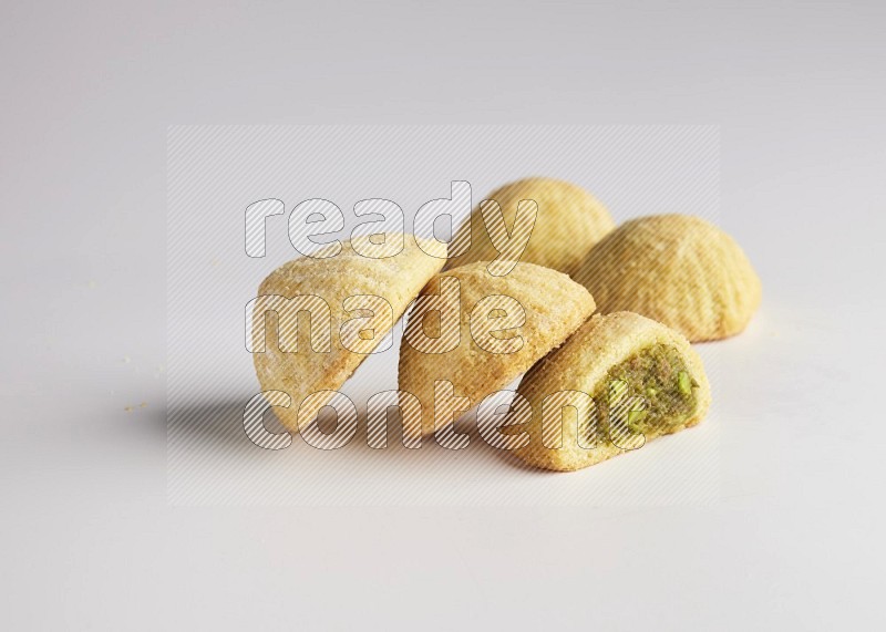 Five Pieces of Maamoul filled with pistachio  paste one of them is cut direct on white background