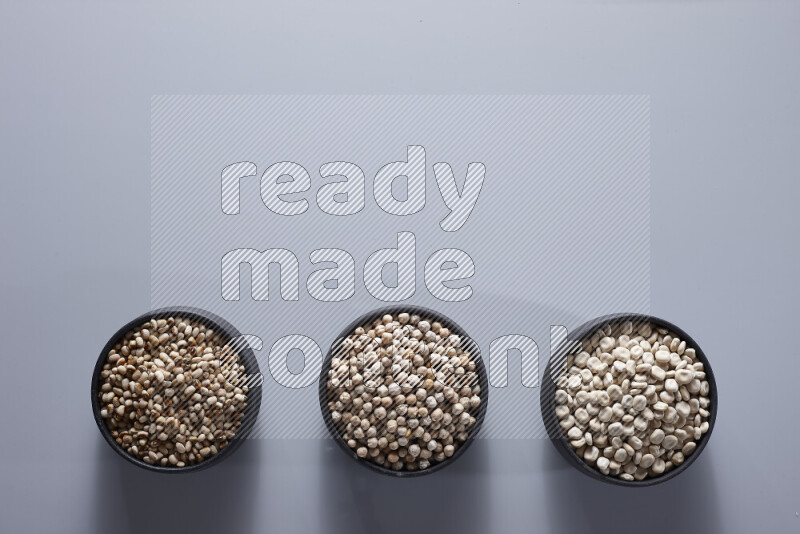 Legumes in pottery bowls on light grey background
