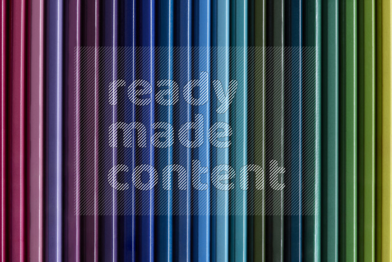 مجموعة من أقلام الرصاص الملونة مرتبة لتعرض تدرجا من الألوان المختلفة علي خلفية رمادية