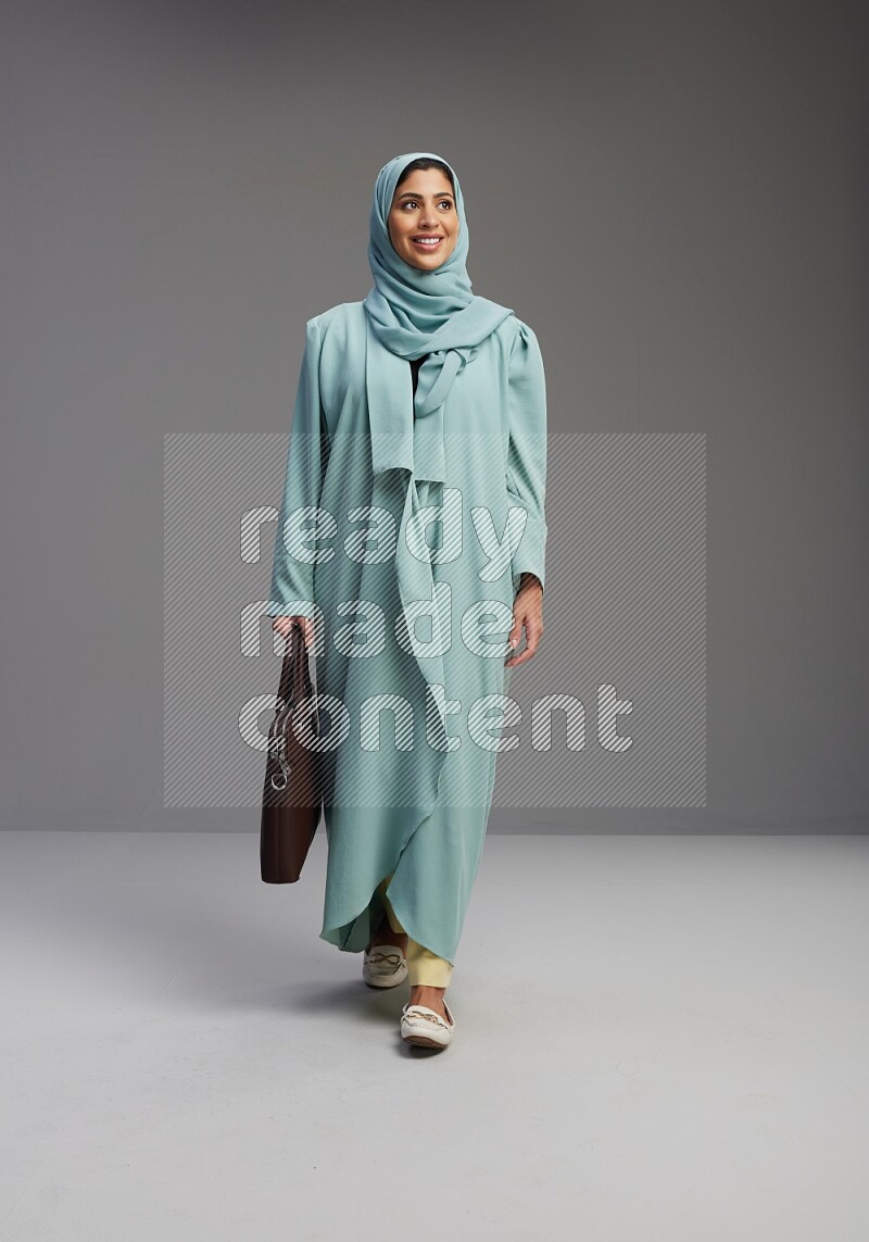 Saudi Woman wearing Abaya standing holding bag on Gray background