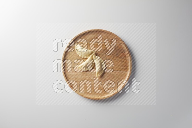 Three Sambosas on a wooden round plate on a white background
