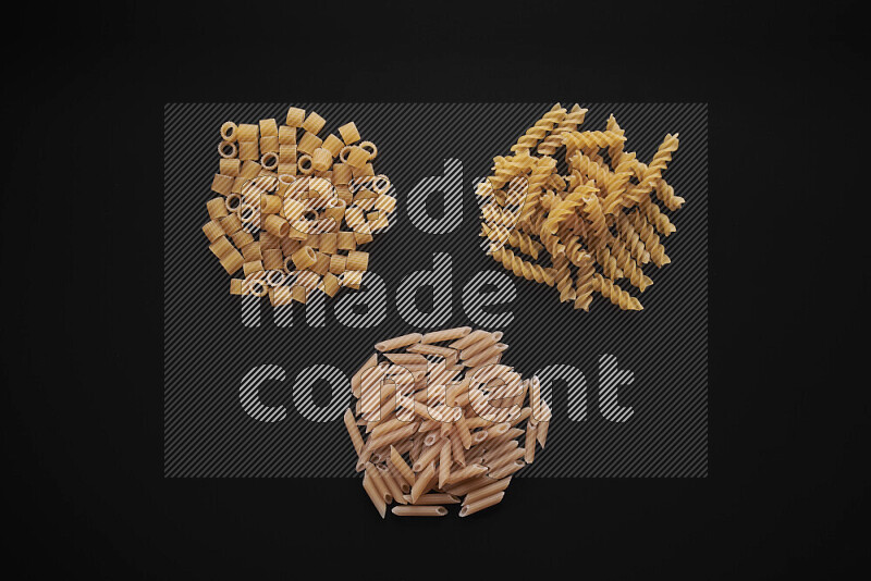 Different pasta types in bunches on black background