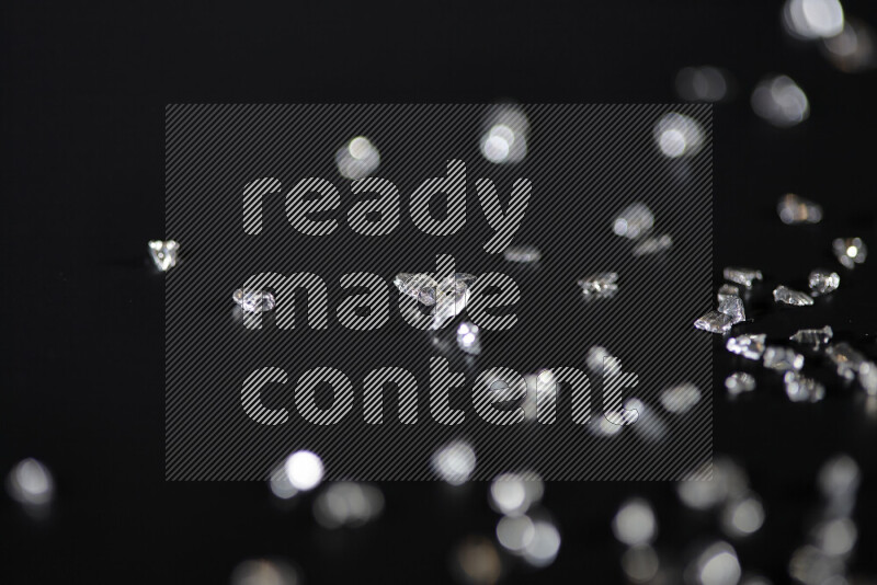 Silver shimmering fragments of glass scattered on a black background