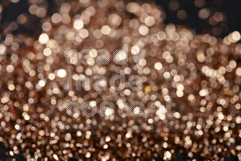 Bronze shimmering fragments of glass scattered on a black background