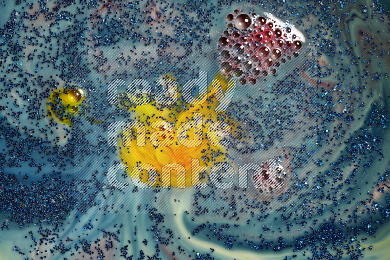 A close-up of sparkling blue glitter scattered on swirling blue and yellow background