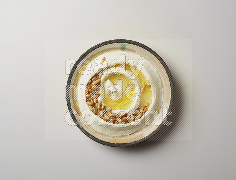 Lebnah garnished with pine nuts in a pottery plate on a white background