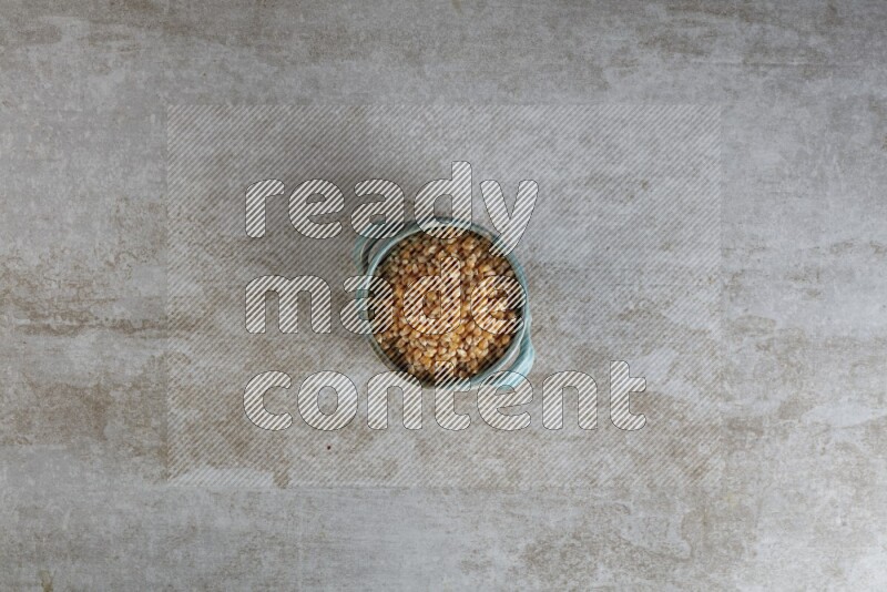 corn kernel in a multi-colored handheld ceramic bowl on a grey textured countertop