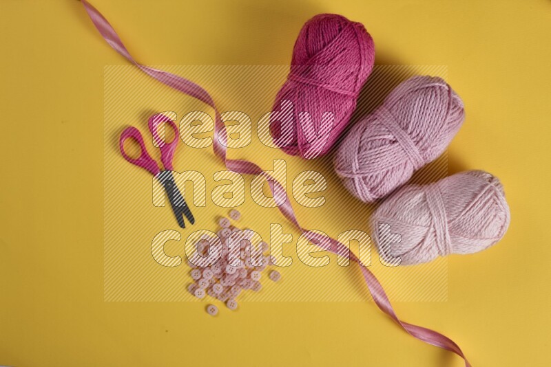 مجموعة من أدوات الخياطة والتفصيل زهرية اللون على خلفية صفراء