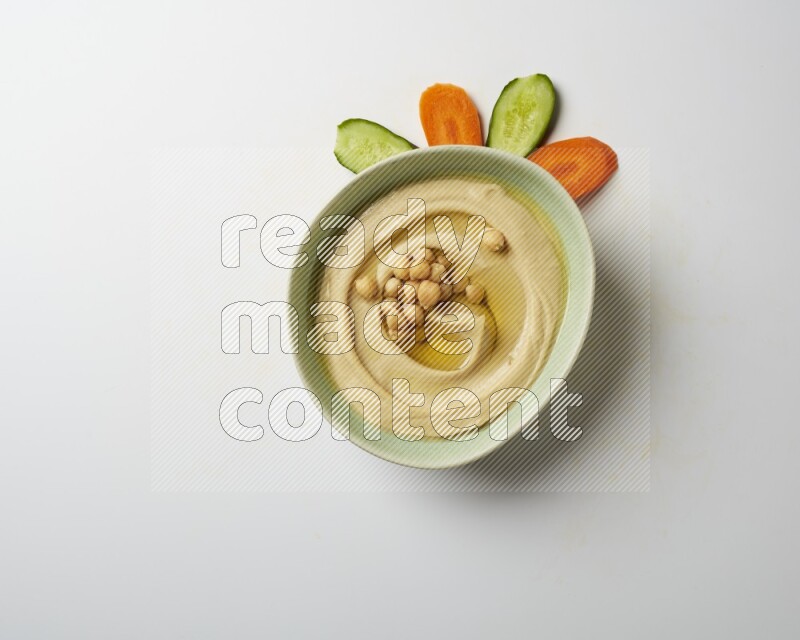 Hummus in a green plate garnished with roasted chickpeas  on a white background