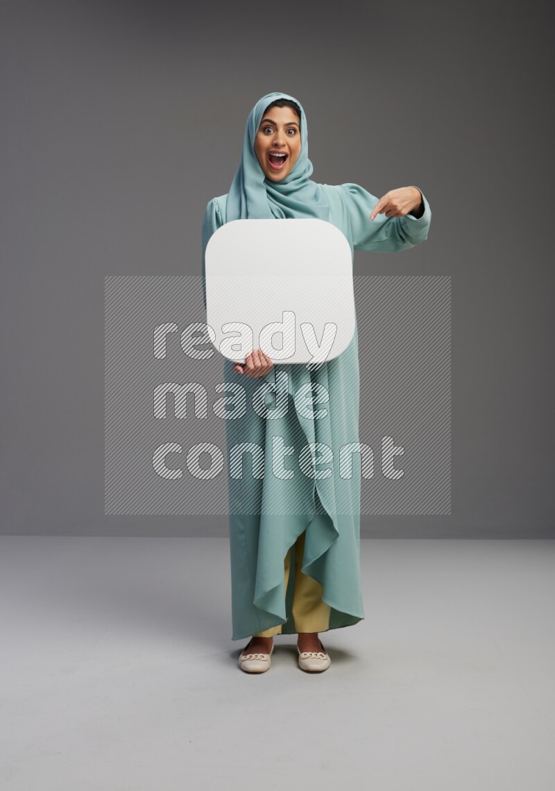 Saudi Woman wearing Abaya standing holding social media sign on Gray background