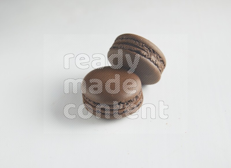 45º Shot of two Brown Dark Chocolate macarons on white background