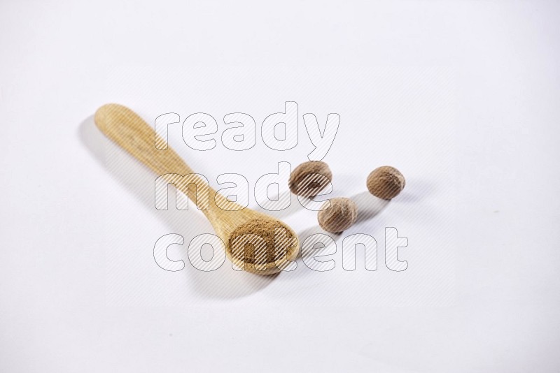 A wooden spoon full of nutmeg powder with nutmeg seeds beside it on a white flooring in different angles