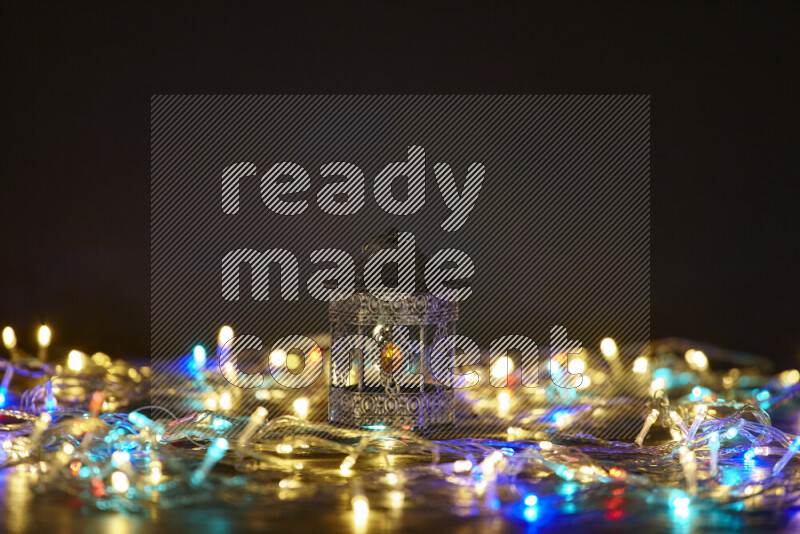 A traditional ramadan lantern surrounded by glowing fairy lights in a dark setup