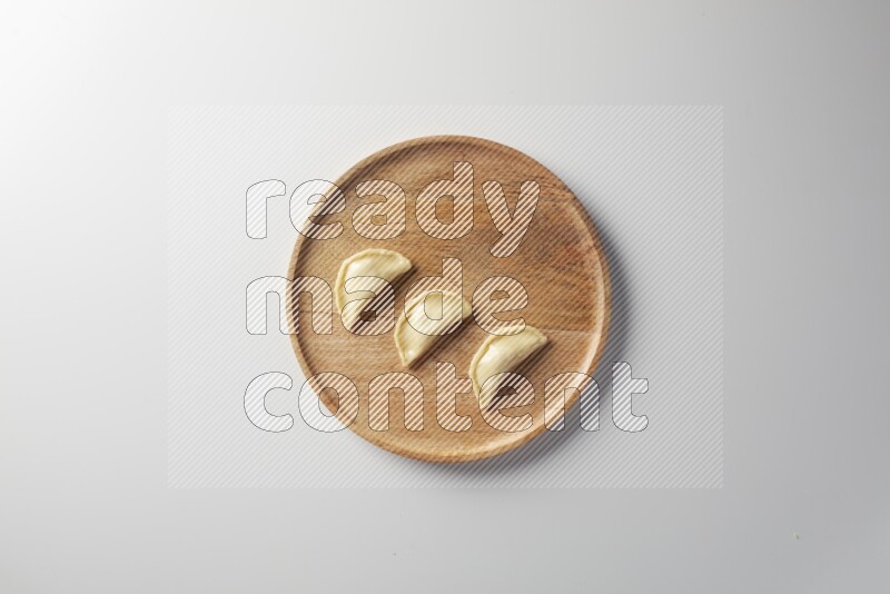 Three Sambosas on a wooden round plate on a white background