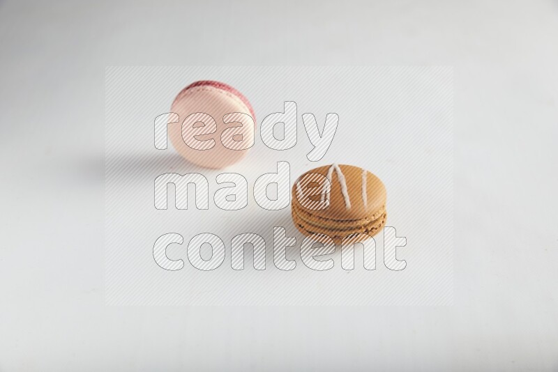 45º Shot of of two assorted Brown Irish Cream, and Pink Litchi Raspberry macarons on white background