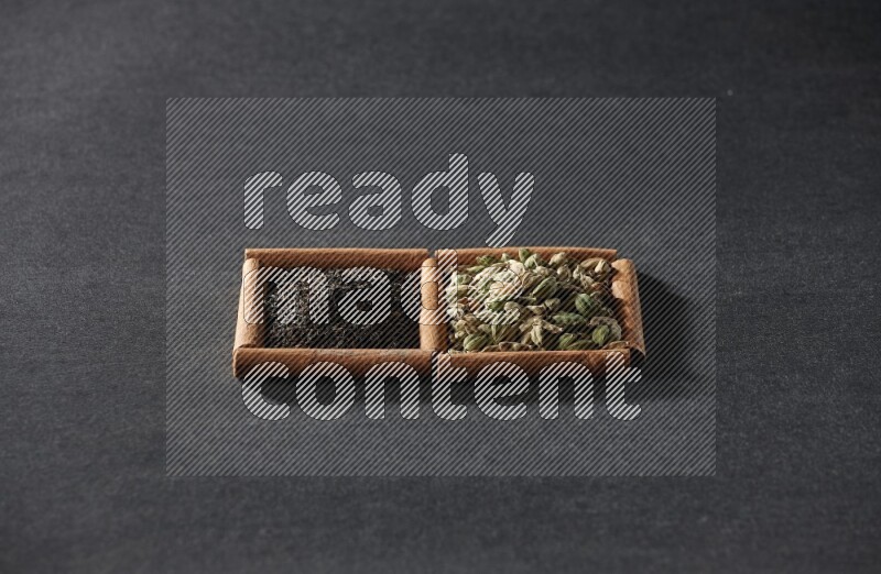 2 squares of cinnamon sticks full of cardamom and black tea on black flooring