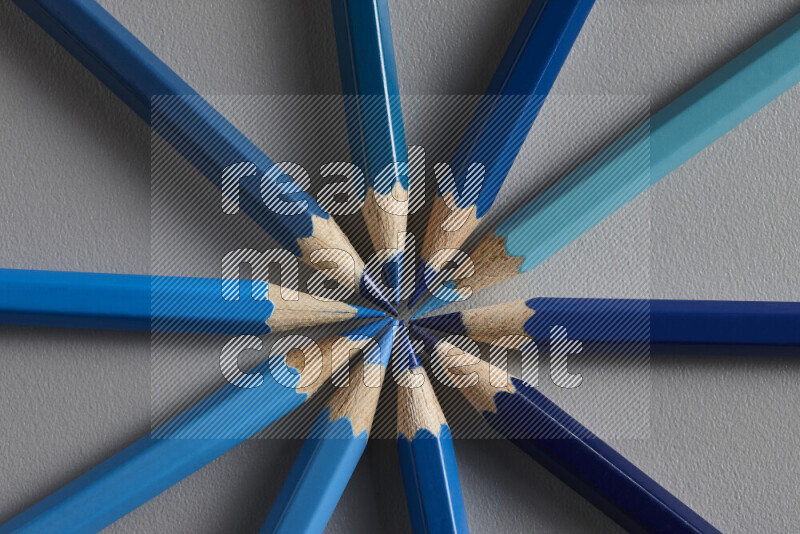 An arrangement of colored pencils in shades of blue on grey background