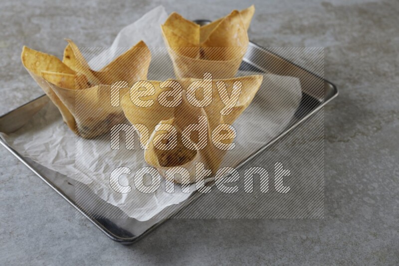 wonton cups on parchment paper in stainless tray on grey textured counter top