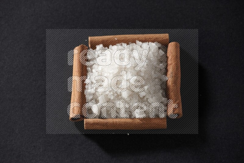A single square of cinnamon sticks full of salt on black flooring