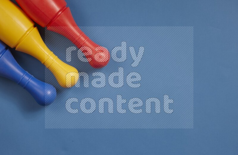 أوتاد البولينج البلاستيكية الملونة علي خلفيات ملونة مختلفة (ألعاب أطفال)