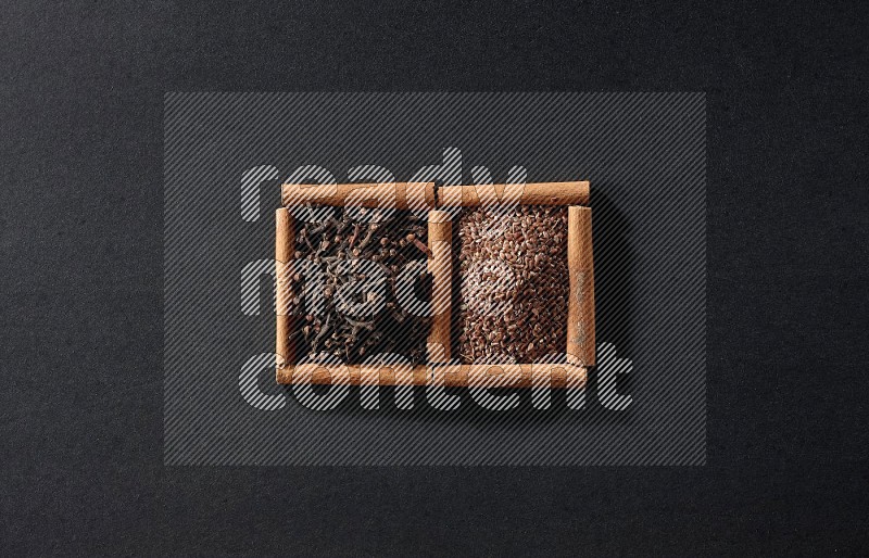 2 squares of cinnamon sticks full of flaxseeds and cloves on black flooring