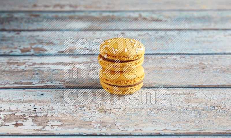 45º Shot of two Yellow Piña Colada macarons on light blue wooden background