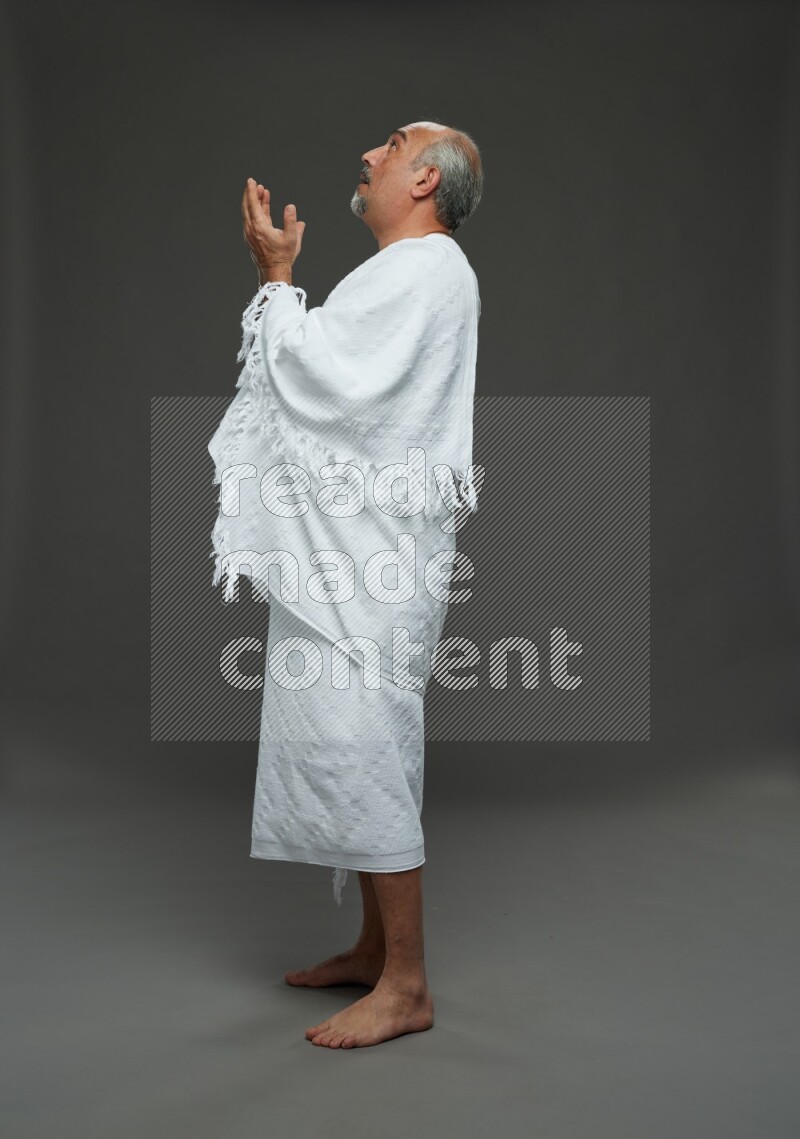 A man wearing Ehram Standing dua'a on gray background