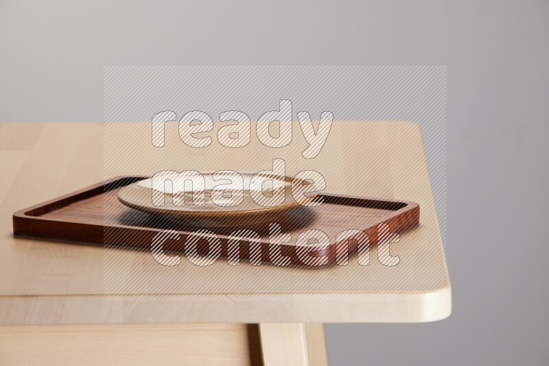 multi-colored pottery Plate placed on a rectangular wooden tray on the edge of wooden table