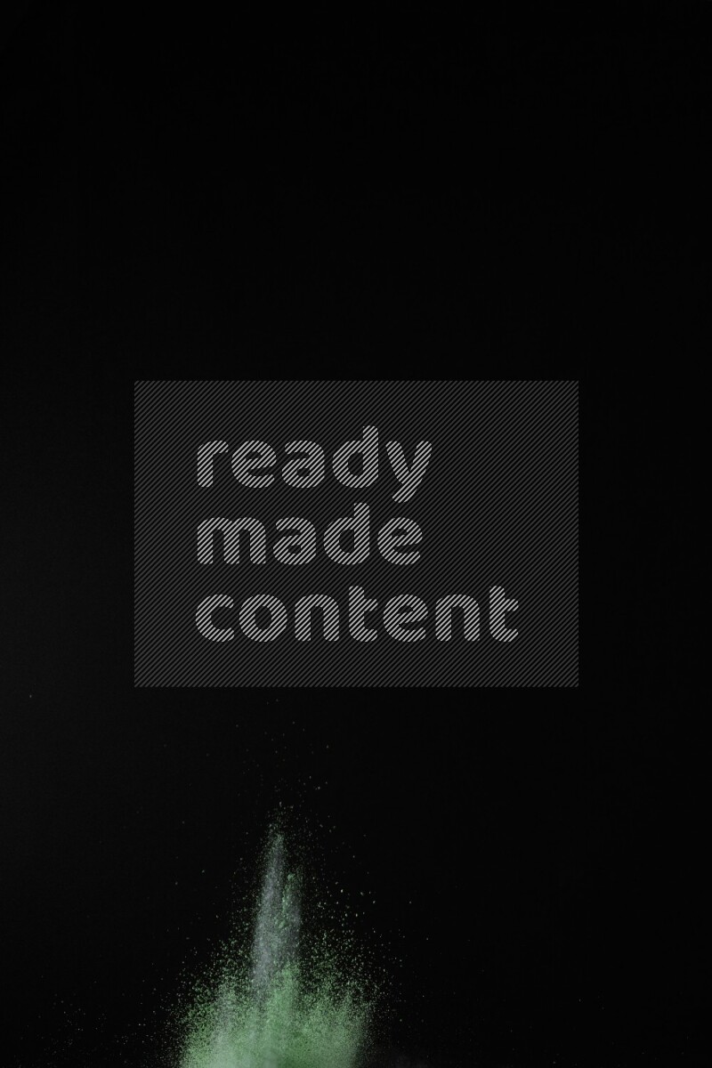 A side view of green powder explosion on black background