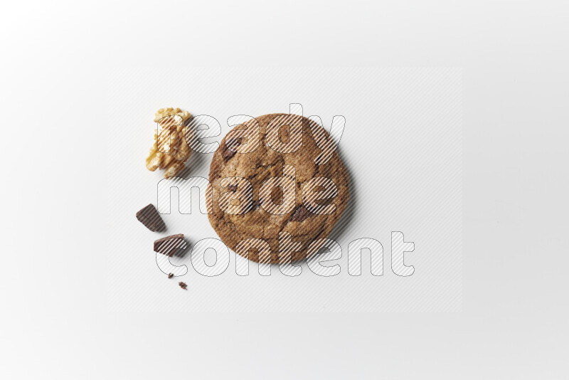 A single chocolate chips cookie with chocolate and walnuts beside it on a white background